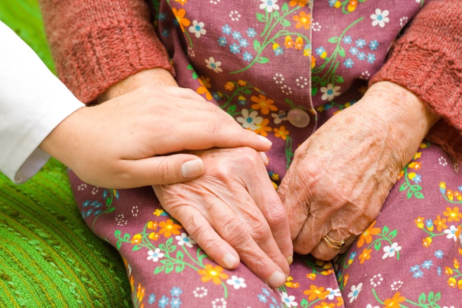 Cuidadora ayudando a anciana en vivienda comunitaria en Ourense